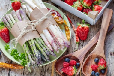 ahşap masa üzerinde sağlıklı organik kuşkonmaz ve taze olgun çilek üstten görünüm 