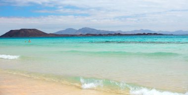 Kumlu sahili ve ufukta dağları olan inanılmaz bir deniz manzarası.