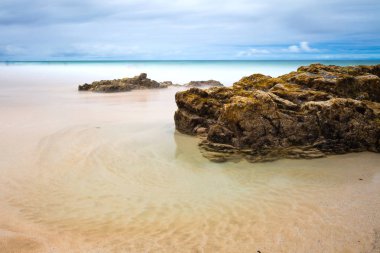 Güzel doğal deniz manzarası ve gündoğumu sırasında taşlarla kumlu plaj 