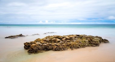 Muhteşem doğal deniz manzarası ve gündoğumu sırasında taşlarla kumlu plaj 