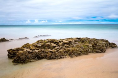 Muhteşem doğal deniz manzarası ve gündoğumu sırasında taşlarla kumlu plaj