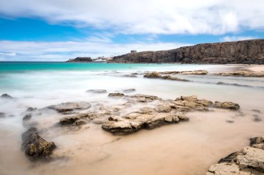 Kumlu sahili, uçurumları ve mavi deniz dalgaları olan harika bir deniz manzarası.  