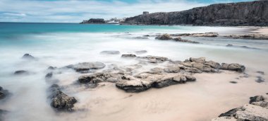 Kumlu sahili, uçurumları ve mavi deniz dalgaları olan harika bir deniz manzarası. 