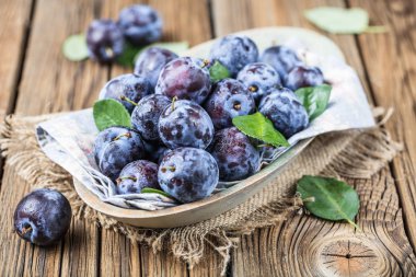 Taze yaprak yeşil rustik tablo hasır sepet ve hlaf erik erik yığını.