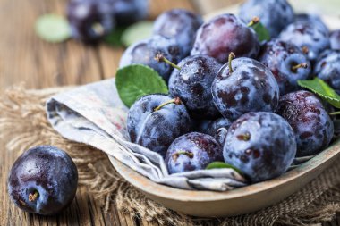 Taze yaprak yeşil rustik tablo hasır sepet ve hlaf erik erik yığını.