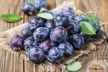 Taze yaprak yeşil rustik tablo hasır sepet ve hlaf erik erik yığını.