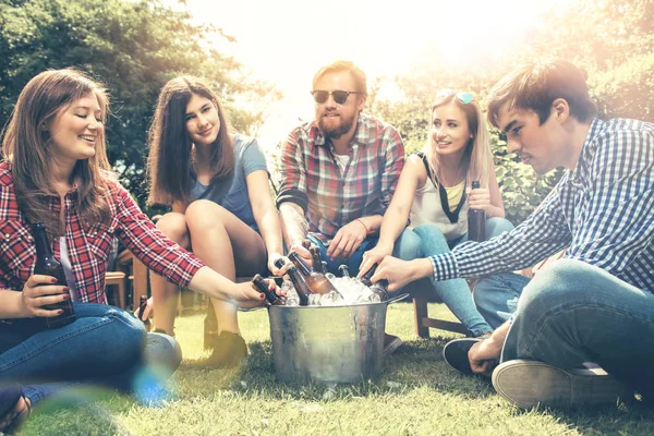 年轻的朋友一起出去玩 一起坐在草地上 一起喝啤酒 — 图库照片