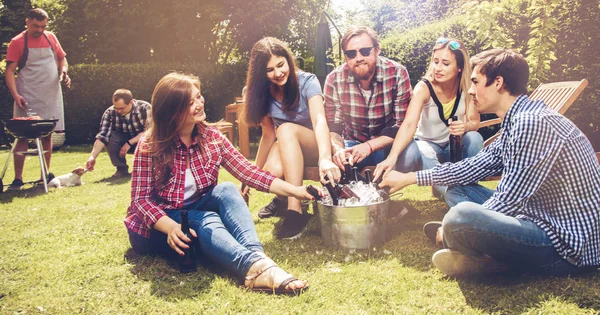 快乐的年轻朋友们一起出去玩 一起坐在草地上 一起喝啤酒 — 图库照片