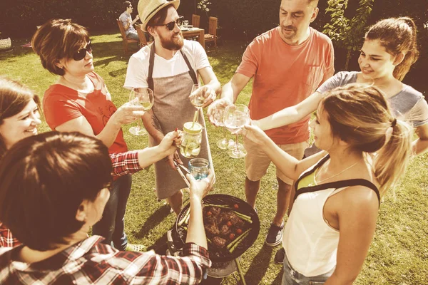 屋外の庭のバーベキューやアルコール飲料で笑っている友人のグループ — ストック写真