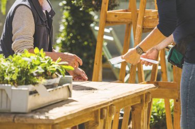 Çiçekçide saksıda çiçeklerle çalışan kadın çiçekçinin kısmi görüntüsü 