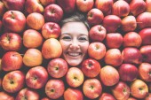 Potravinářský průmysl. Tvář smějící se mladá žena v rovině apple. Creative pozadí s červenými jablky