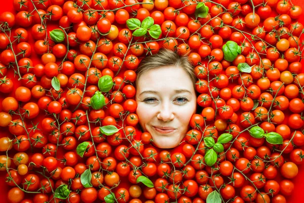 Woman with tomatoes, concept for food industry. Face of laughing woman in tomato surface.
