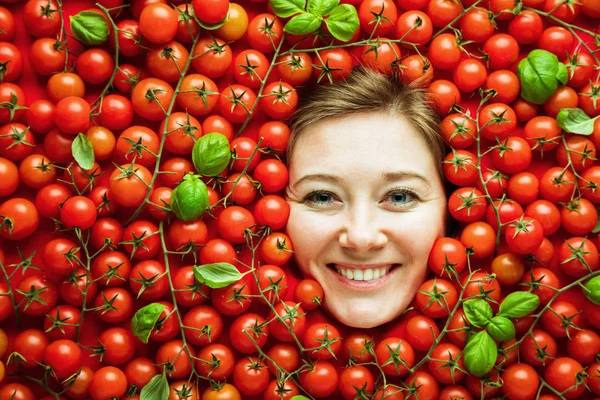 Woman with tomatoes, concept for food industry. Face of laughing woman in tomato surface.