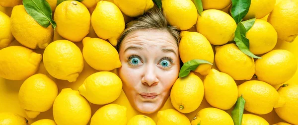Woman with lemons, concept for food industry. Face of laughing woman in lemon surface