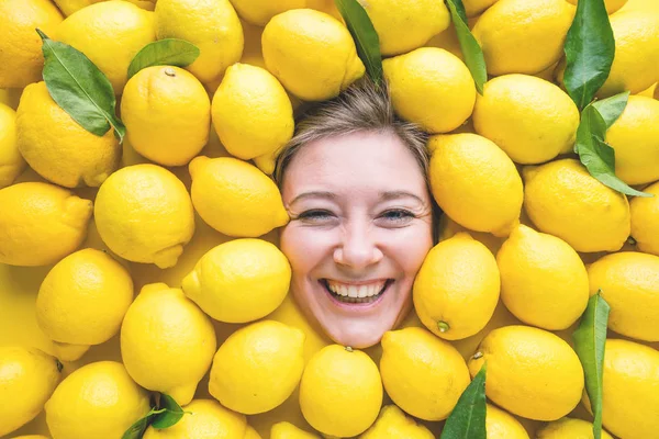 Woman with lemons, concept for food industry. Face of laughing woman in lemon surface