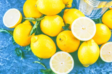 mavi yüzeyinde boş cam ve taze olgun limon üstten görünüm  