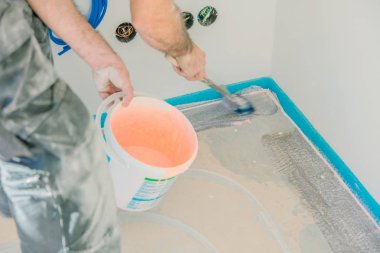 Beton zemin üzerinde rulo ile astar koyarak İşçi Kırpılmış atış. Yapım aşamasında olan ev.