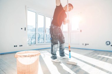 Yenileme sırasında beton zemine silindirli astar koyan işçi