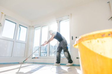 Ev yapım aşamasında. Beton zemine makaralı astar koyan işçi