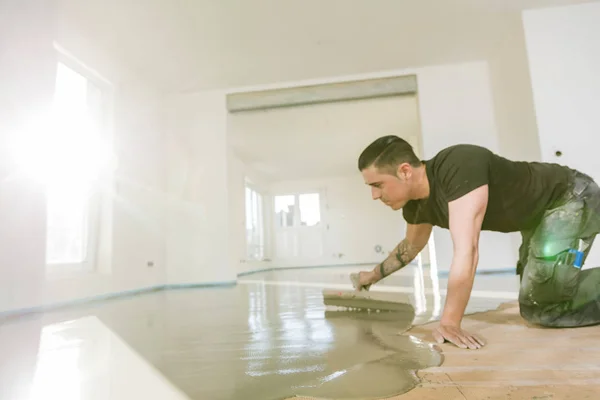 Plasterer during floor covering working with cement mortar