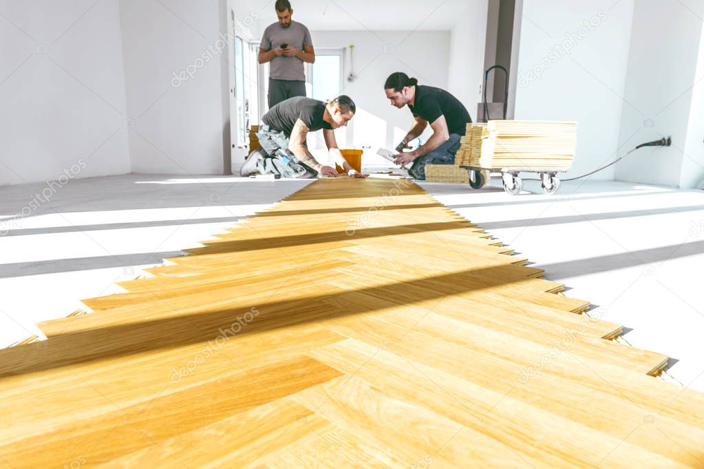 male workers during process of parquet alignment 