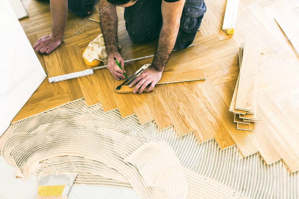 cropped shot of male workers during process of parquet alignment 