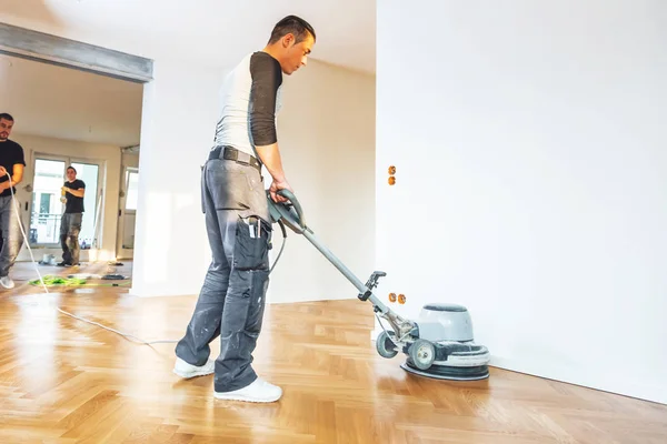 男性は ホーム改善中にオークの寄木細工の床をニス — ストック写真