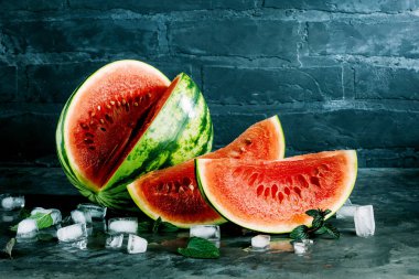 nane yaprakları ve buz küpleri ile taze organik karpuz gri yüzeyi ve tuğla duvar arka plan üzerinde görmek