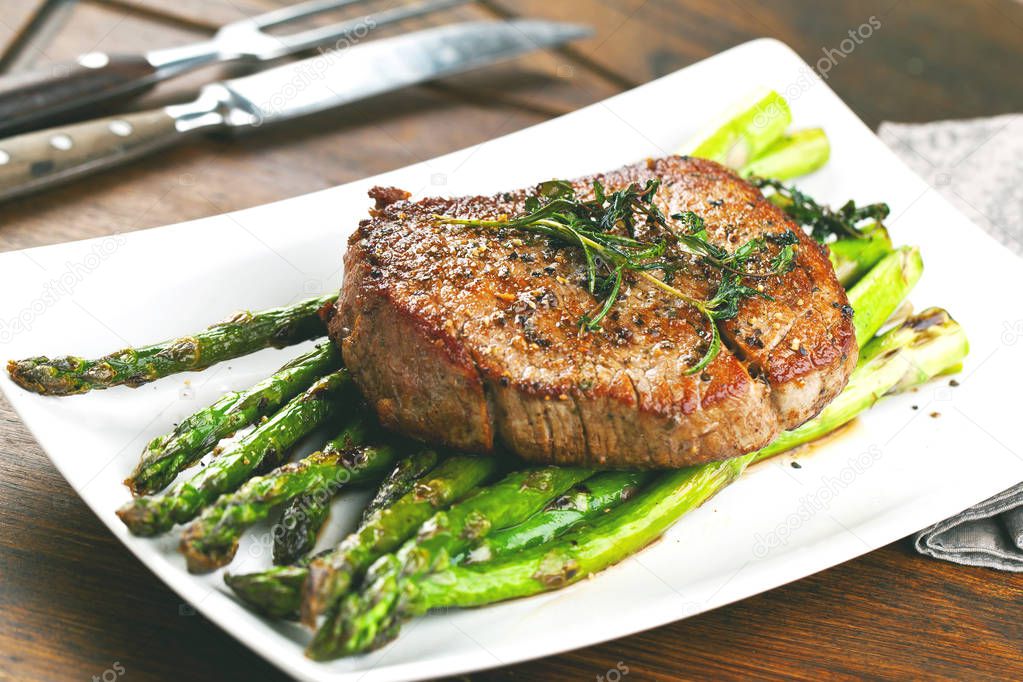 close-up view of gourmet grilled steak and asparagus on white plate