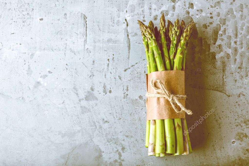 top view of fresh raw green tied asparagus on grey background  