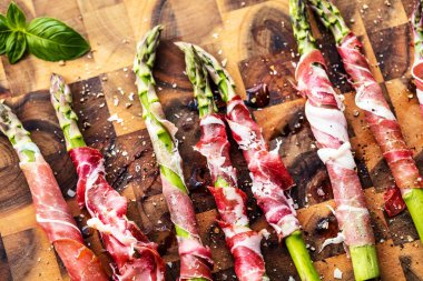 taze kuşkonmaz pastırma ve fesleğen yaprakları ahşap tahta üzerinde sarılı Üstten Görünüm 