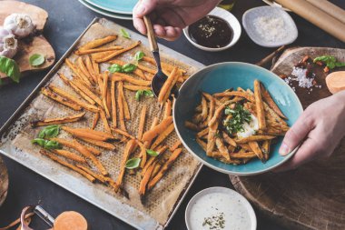 fesleğen yaprakları ve soslar ile tatlı patates yemek kişinin kırpılmış atış 