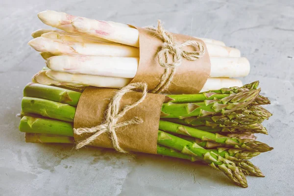 bunches of green and white asparagus on grey surface, close-up