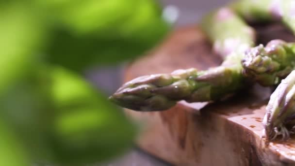 Nahaufnahme Von Frischem Nassem Grünen Spargel Mit Salz Auf Holzbrett — Stockvideo