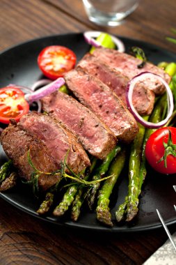 yakından görmek lezzetli Barbekü T-bone biftek dilimlenmiş yeşil kuşkonmaz ve sebze ile
