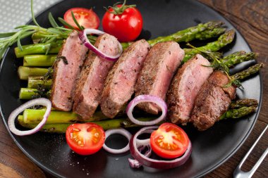 yakından görmek lezzetli Barbekü T-bone biftek dilimlenmiş yeşil kuşkonmaz ve sebze ile
