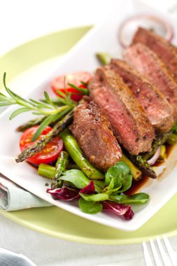 yakından görmek lezzetli Barbekü T-bone biftek dilimlenmiş yeşil kuşkonmaz ve sebze ile