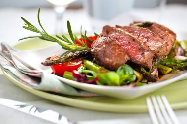 yakından görmek lezzetli Barbekü T-bone biftek dilimlenmiş yeşil kuşkonmaz ve sebze ile