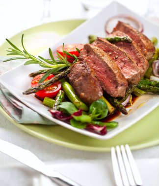 yakından görmek lezzetli Barbekü T-bone biftek dilimlenmiş yeşil kuşkonmaz ve sebze ile