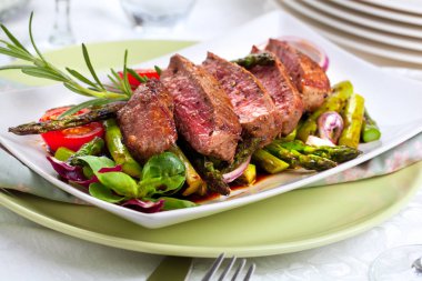 yakından görmek lezzetli Barbekü T-bone biftek dilimlenmiş yeşil kuşkonmaz ve sebze ile