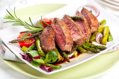 yakından görmek lezzetli Barbekü T-bone biftek dilimlenmiş yeşil kuşkonmaz ve sebze ile