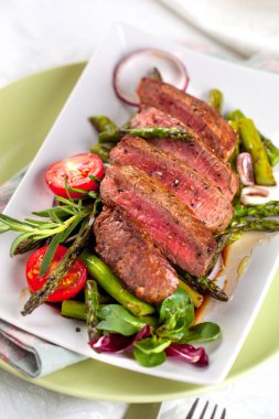 yakından görmek lezzetli Barbekü T-bone biftek dilimlenmiş yeşil kuşkonmaz ve sebze ile