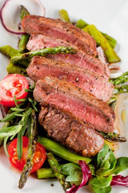 lezzetli dilimlenmiş biftek ızgara kuşkonmaz, domates ve otlar ile üstten görünüm plaka üzerinde 
