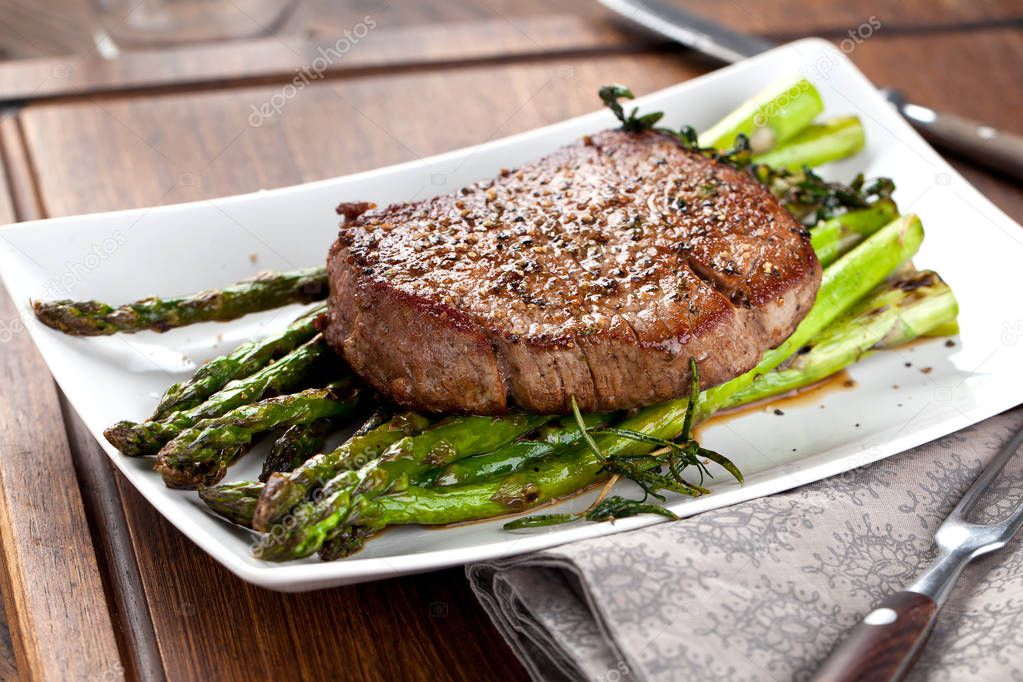 close-up view of delicious grilled steak with green asparagus on plate