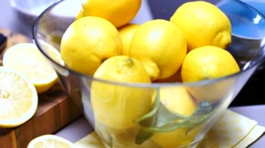 taze olgun sulu bütün ve yarıya limon, yeşil yaprakları ve masada cam kase
