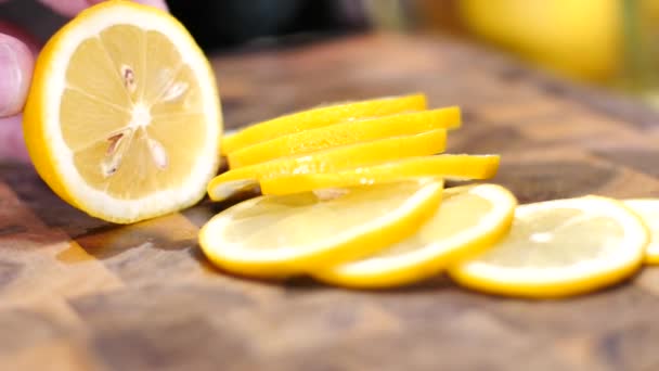 まな板の上にナイフとスライスの新鮮な熟したレモンを保持している人の部分拡大 — ストック動画