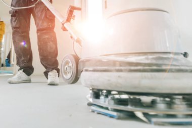 Aletle meşe parke zemini cilalayan adamın kırpılmış görüntüsü.