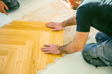 Evin tadilatı sırasında meşe parke döşeyen işçilerin kırpılmış görüntüsü  