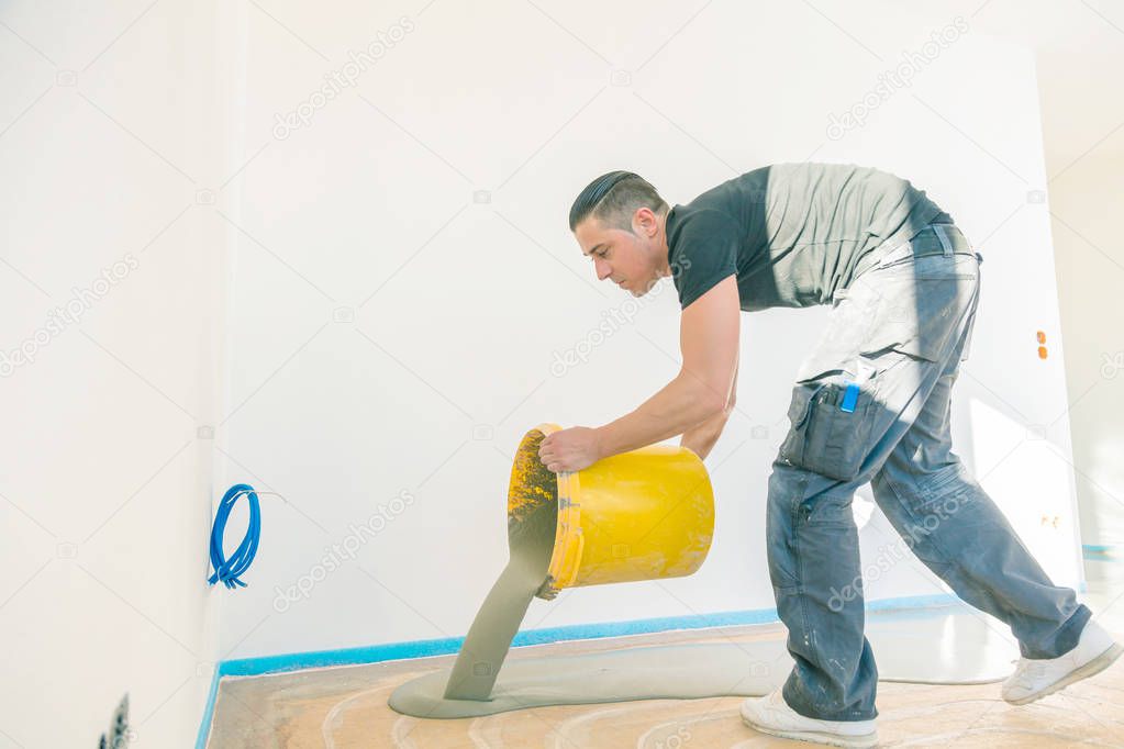 worker working with self-levelling cement mortar during floor covering 