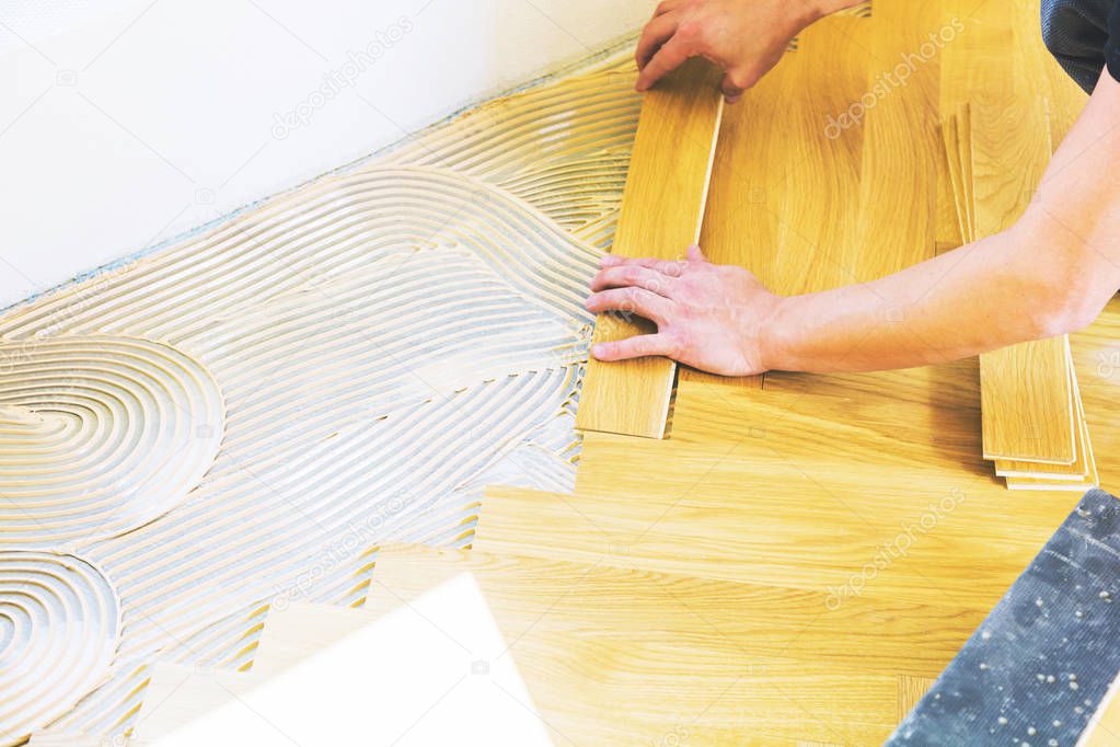 cropped shot of man installing oak parquet floor during home improvement 